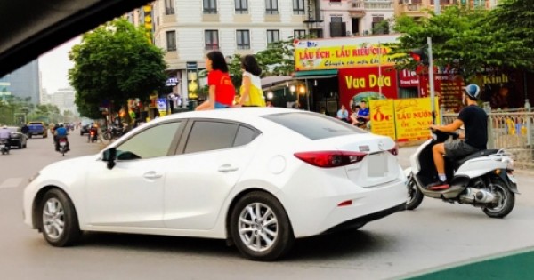 Rợn người cảnh hai bé gái ung dung ngồi nóc ôtô chạy giữa phố Hà Nội