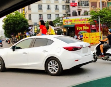 Rợn người cảnh hai bé gái ung dung ngồi nóc ôtô chạy giữa phố Hà Nội