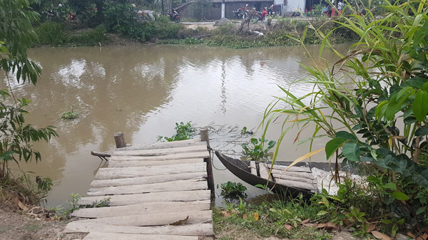 Lối đi và chiếc xuồng chông chênh là phương tiện duy nhất để Cụ Võ Thị Sáu-Mẹ Liệt sĩ và người dân trong xã qua sông hàng ngày.