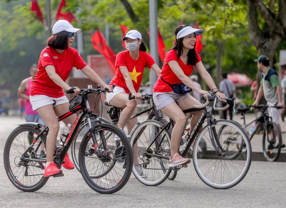 Người dân Thủ đô trong trang phục cờ đỏ, sao vàng đạp xe trên đường phố Hà Nội.